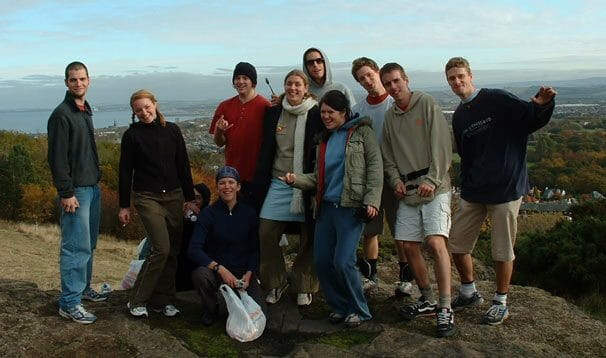 A group of teenagers enjoying an outdoor adventure on a hilltop with scenic views.