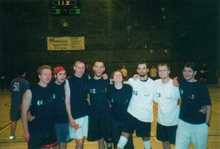 Team of athletes standing together in sportswear after a game on an indoor court. | Group of male and female players posing after a basketball match. | A diverse sports team celebrating victory indoors, highlighting teamwork and athleticism. | Relevance: The image is relevant as it showcases a sports team, aligning with Mohawks Ultimate and their focus on sports.