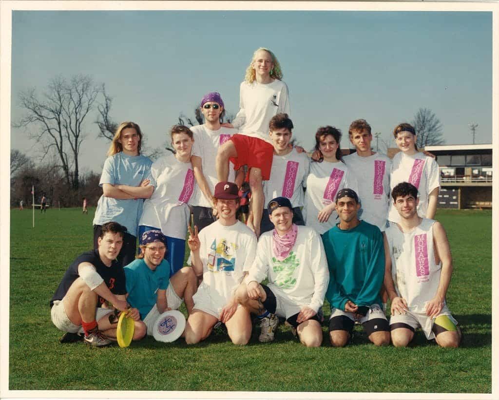 Youth Ultimate Frisbee team posing on a sports field, showcasing team spirit and colours.